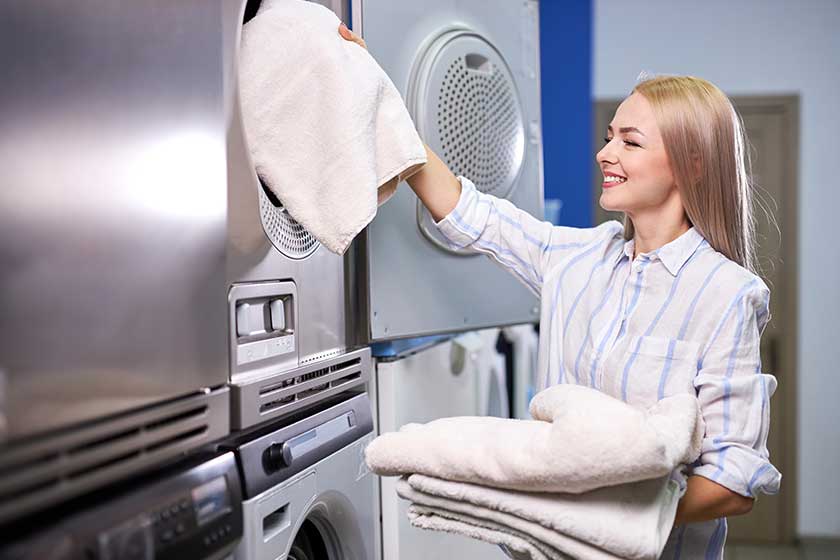Pretty woman loading linen towels into washing machine